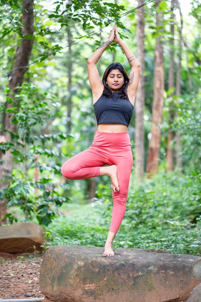 The Art of Drawing Readers In: Your attractive post title goes here Female doing yoga tree pose on a rock in a lush forest setting, promoting mindfulness and fitness.